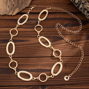 Detail view of gold hollow circular metal waist chain on a vintage wooden table background