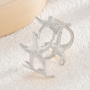 Starfish open upper arm cuff with textured silver metallic finish on sandy fabric