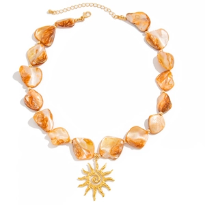 Bohemian sun pendant necklace with irregular amber shell beads on a white background