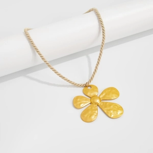Detail of matte gold flower pendant with hammered texture on a twisted rope chain necklace