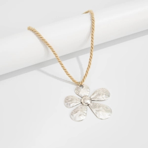 Detailed view of large silver flower pendant with hammered texture and golden twist chain