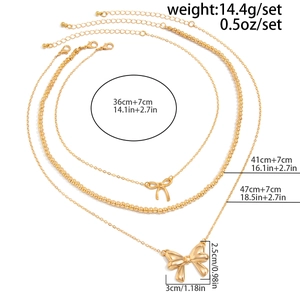 Detailed size chart for triple-layered gold bow necklace featuring pearls and metal charms