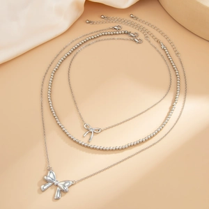 Detailed view of layered silver bow pendant necklace with bead chain and lobster clasp
