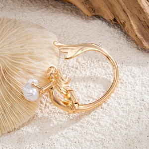 Manchette d'oreille sirène dorée avec perle sur fond de coquillages et de coraux