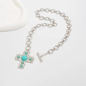 Detalle del collar con colgante de cruz plateado, turquesas y cierre de tipo OT