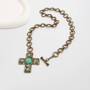 Detalle del collar de cruz de bronce vintage con cuentas turquesas y cierre de palanca