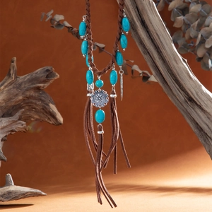 Detailed view of bohemian turquoise pendant with fringe tassels on a wooden branch
