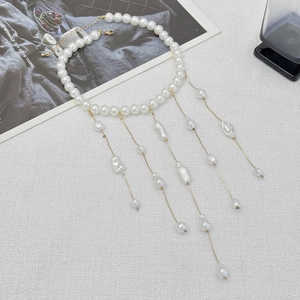 Détail d'un collier à pompons en perles élégant avec chaînes dorées et perles baroques