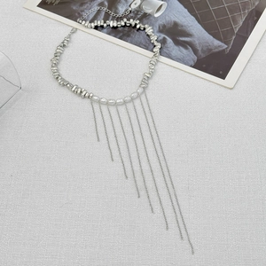 Détail du collier ras du cou avec perles argentées et longues franges de glands
