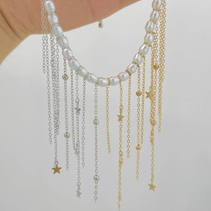 Détail du collier de perles avec pompons métalliques et breloques étoiles sur la chaîne