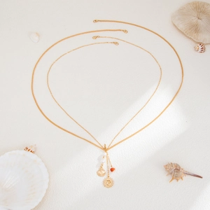 Detail of gold multi-layer body chain with shell, sun pendant and white pearl accents