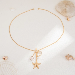 Golden multi-layer body chain with starfish and shell pendants on a sandy background