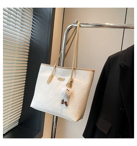 Detail of white tote bag featuring embossed cartoon motifs and Seamager metal logo
