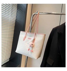 White tote bag with cartoon graffiti embossing, pink straps and plush monster charm detail