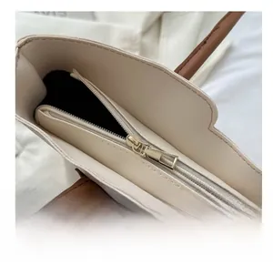 Detail view of smooth silver nylon zipper and light gold hardware on a beige tote bag