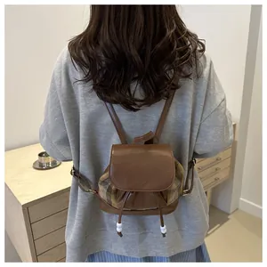 Detail of vintage checkered backpack featuring leather flap and fashion inscription