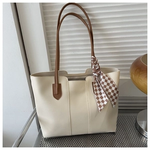 Minimalist off-white tote bag with brown straps and checkered silk scarf on a sleek desk