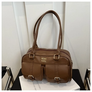 Detail view of brown faux leather shoulder bag featuring dual buckled front pockets