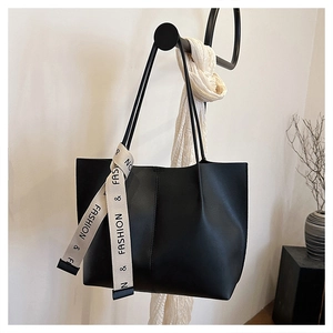 Détail du sac cabas noir avec couture verticale et accent de foulard en soie imprimé
