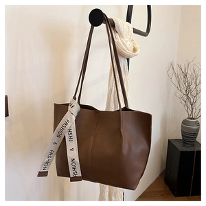 Détail d'un grand sac cabas marron foncé avec ruban décoratif sur un cintre élégant