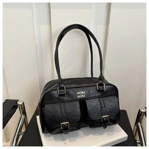 Detail of glossy black leather handbag showing dual front pockets and gold metal buckles