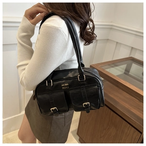 Detail of black retro shoulder bag with twin buckle pockets and gold brand lettering