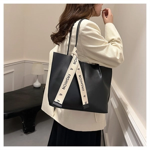 Détail du sac cabas noir minimaliste avec un ruban beige chic sur la poignée élégante
