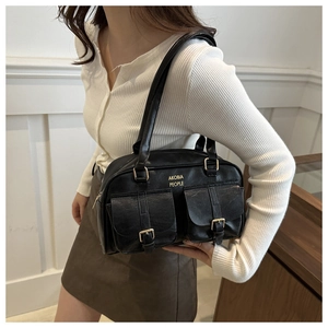 Detail shot of black faux leather shoulder bag featuring utility pockets and gold hardware