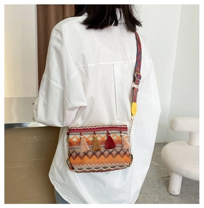Detail of bohemian woven crossbody bag with colorful tassels and wide ethnic strap