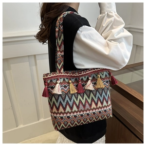 Dettaglio borsa tote boho intrecciata con motivi a zig-zag colorati e nappe decorative pendenti
