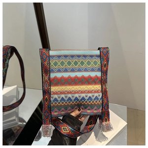 Détail d'un sac à main ethnique tissé avec motifs géométriques et pompons colorés