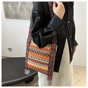 Gros plan sur un sac bohème tissé avec des motifs géométriques vibrants et des glands