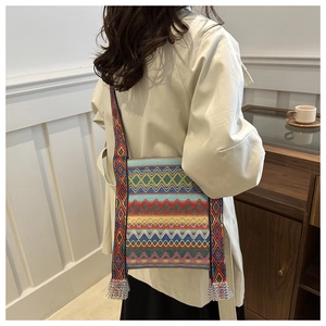 Détail du sac ethnique en toile avec motifs géométriques colorés et pompons argentés