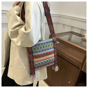 Détail de la broderie ethnique sur un sac bandoulière en toile avec sangle à pompons