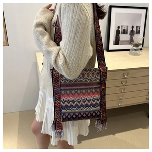 Gros plan du sac bandoulière bohème tissé avec motifs géométriques et pompon