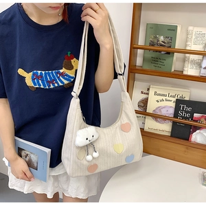 Detail of canvas tote bag with colorful heart patches and plush cloud charm on model