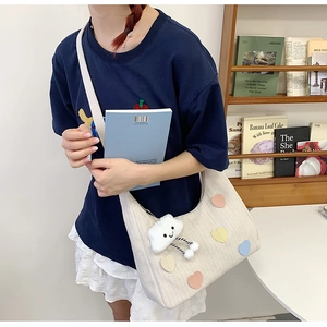 Detail of canvas tote bag with heart patches and cloud charm in minimalist setting