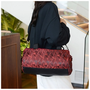 Large capacity red camo nylon travel bag shown in hand-carry style in a bright cafe