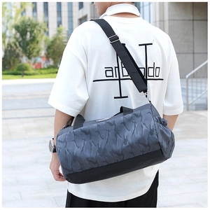 Modern grey camouflage travel duffel bag with wide straps shown on a male model