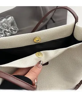 Dettaglio della chiusura magnetica dorata e trama intrecciata su borsa tote crema