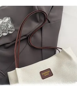 Dettaglio borsa tote intrecciata bianca con tracolla marrone e targhetta logo