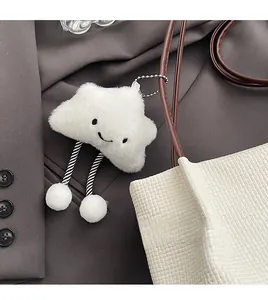Dettaglio del ciondolo a nuvola in peluche bianco con catena su una borsa in tessuto