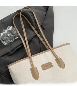 Detail of off-white tote bag featuring cartoon embossing and a leather fashion tag