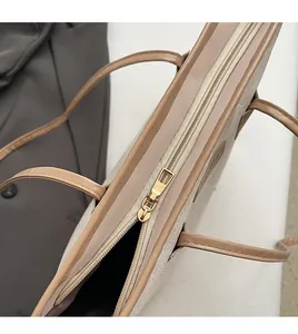 Close-up of smooth gold zipper and embossed beige faux leather on a stylish tote bag