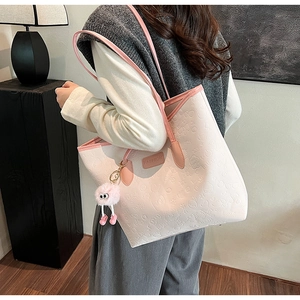 Detailed close-up of pink tote bag with embossed heart patterns and fashion keychain