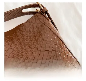 Close-up of golden hardware and embossed texture on a brown shoulder bag