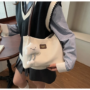 Dettaglio della borsa tote in velluto a coste bianco con manici in pelle marrone e charm
