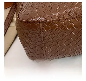 Detail view of woven brown leather tote bag showing high-quality stitching and texture