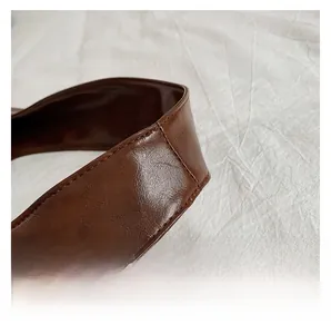 Close-up of durable dark brown wide leather handles with neat stitching on a tote bag