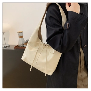 Close-up of cream shoulder bag with bow detail showing leather texture and soft design